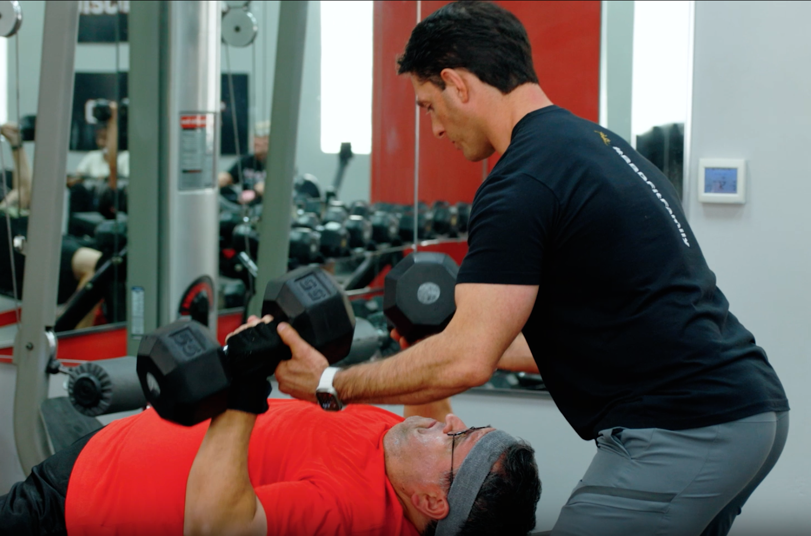 Pflugerville personal trainer spotting his client who is doing a dumbbell bench press.
