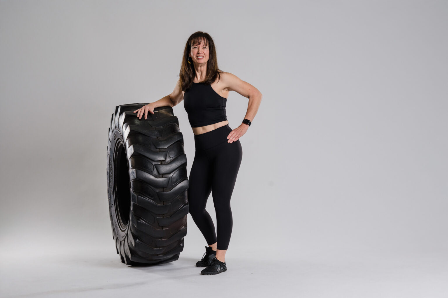 Personal trainer and gym manager in Pflugerville leaning powerfully on a big tire.